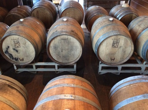 A row of wooden barrels stacked on a rack in a dimly lit room.