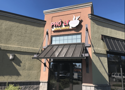 Exterior of Pho Ly Asian Cuisine restaurant with a sign and open door under a clear blue sky.
