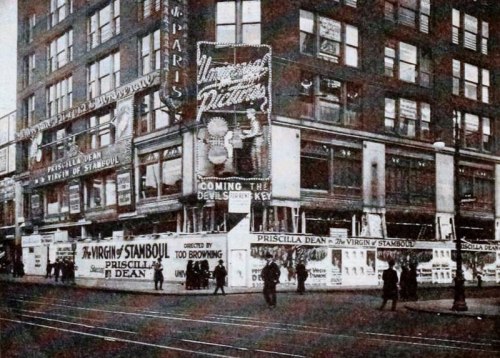 Historic black-and-white photo of a theater building with advertisements for "The Virgin Stamboul" and "Priscilla Dean."