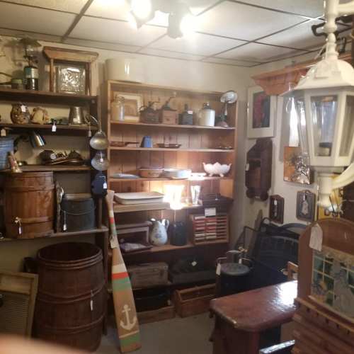 A cozy antique shop filled with wooden shelves, vintage items, and various collectibles, illuminated by soft lighting.
