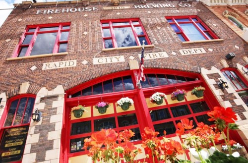 Historic firehouse building with red doors, flowers, and "Firehouse Brewing Co." sign in Rapid City.
