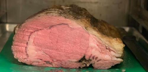 A large, cooked roast with a golden crust and pink interior, resting on a green cutting board.