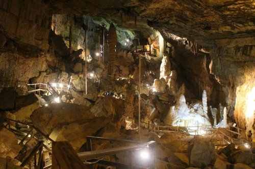 A dimly lit cave interior with rock formations, stalactites, and pathways illuminated by soft lights.