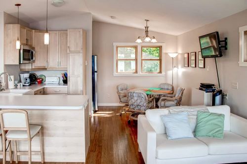 Bright, modern open-concept kitchen and living area with a dining table, comfortable seating, and large windows.