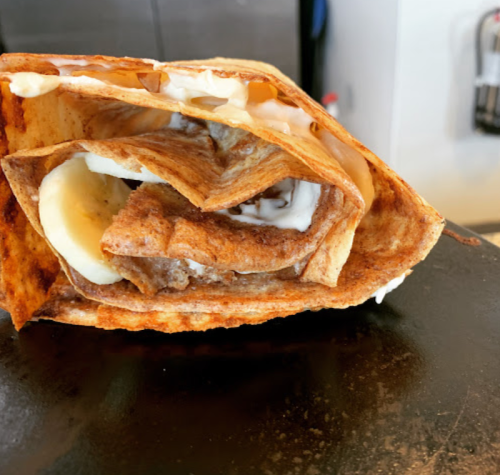 A folded crepe filled with banana slices and a creamy sauce, resting on a flat surface.