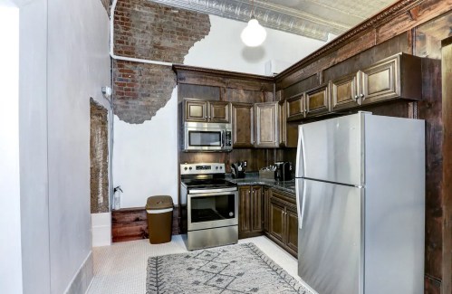 Modern kitchen with dark wood cabinets, stainless steel appliances, and exposed brick wall accents.
