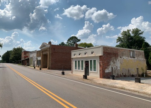 A quiet, empty street lined with old brick buildings under a partly cloudy sky.