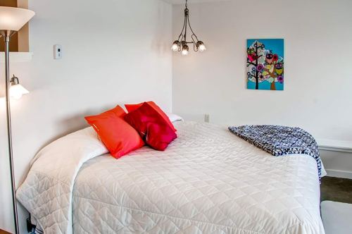 Cozy bedroom featuring a round bed with colorful pillows, a patterned blanket, and modern wall art.