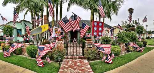 A festive house adorned with numerous American flags and decorations, surrounded by palm trees and a brick pathway.