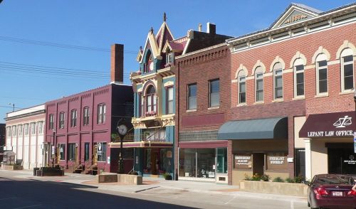 Historic buildings line a sunny street, showcasing a mix of architectural styles and vibrant colors.
