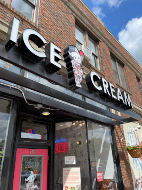 A storefront with a large "ICE CREAM" sign featuring a cartoon character, bright colors, and a welcoming entrance.