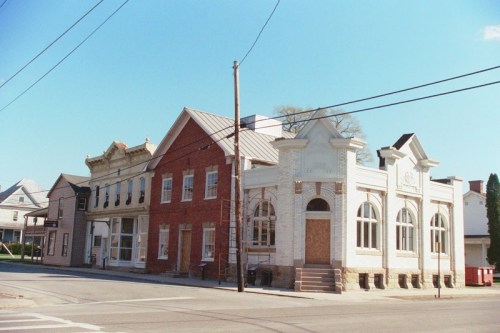 Historic buildings line a street, featuring brick and white facades under a clear blue sky.