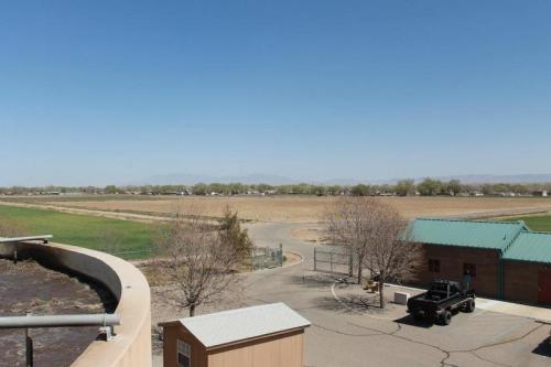 A wide view of a rural landscape with fields, a road, and a building under a clear blue sky.