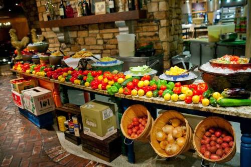 A vibrant display of fresh fruits and vegetables on a buffet table, featuring colorful tomatoes, peppers, and more.