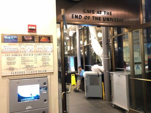 Entrance to the "Cafe at the End of the Universe" with a ticket kiosk and a person working nearby.