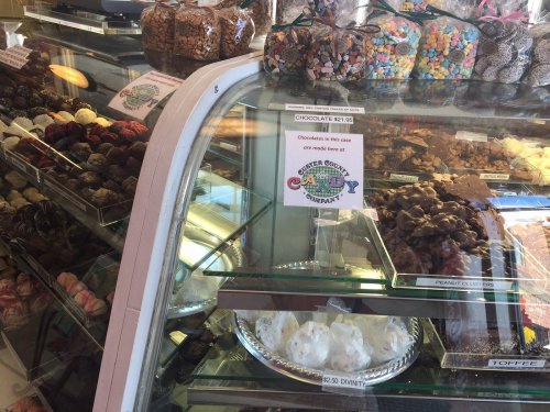 A display case filled with various chocolates and candies, featuring a sign for chocolate prices and divinity treats.