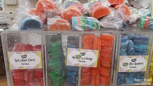 Colorful fruit slice candies in clear containers, labeled Red & Black Cherry, Watermelon & Orange, and Blue Raspberry.