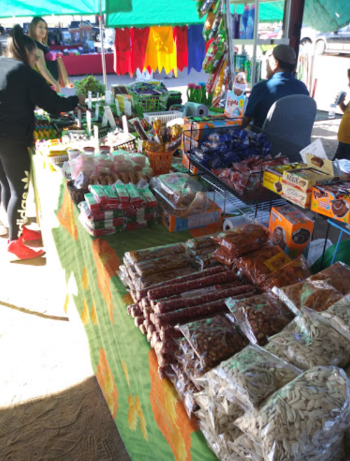 A vibrant market stall filled with various snacks, candies, and dried goods, with shoppers browsing nearby.