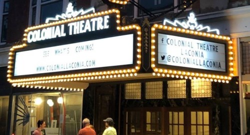 The illuminated marquee of the Colonial Theatre, featuring upcoming events and social media handles.