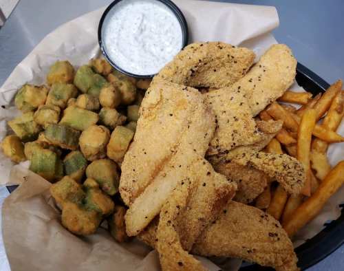 A platter featuring fried fish fillets, crispy okra, French fries, and a small cup of dipping sauce.