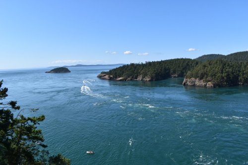 A scenic view of a blue ocean with islands and lush green forests under a clear sky.
