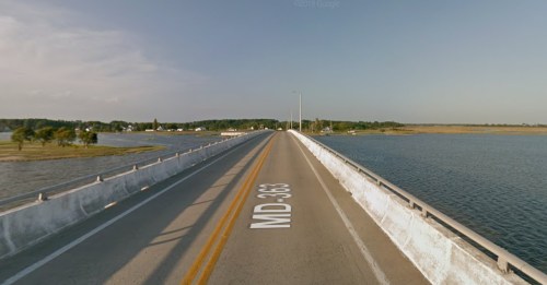 A wide bridge over water, labeled MD 363, with green fields and trees in the background under a clear sky.