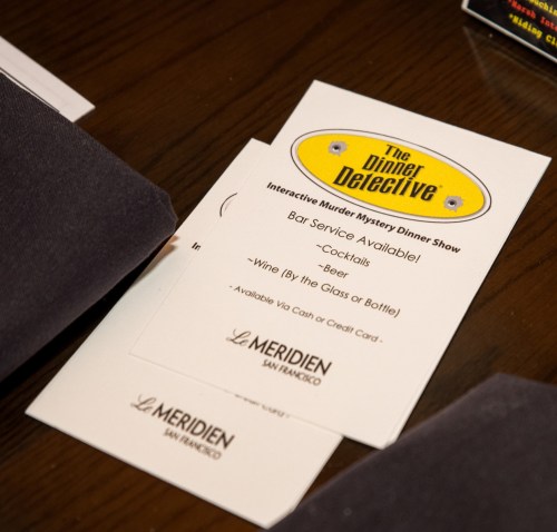 Menu card for "The Dinner Detective" show, listing bar service options: cocktails, beer, and wine available by glass or bottle.