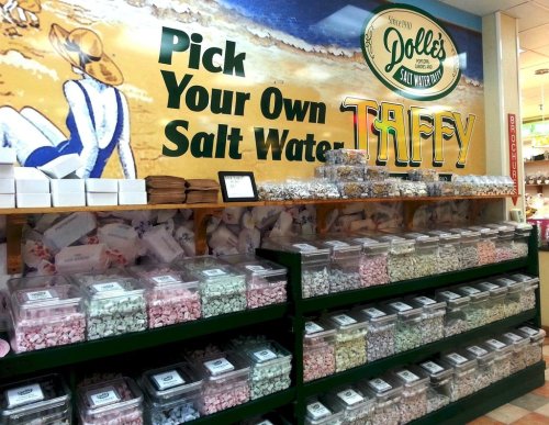 A colorful display of saltwater taffy in clear bins, with a sign that reads "Pick Your Own Salt Water Taffy."