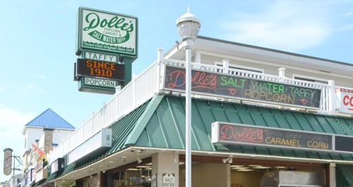 Sign for Dolly's Popcorn and Candy, featuring "Salt Water Taffy" and "Caramel Corn," established in 1910.