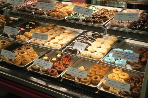 A display case filled with a variety of colorful donuts, including sprinkles, chocolate, and seasonal designs.