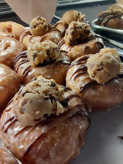 Glazed donuts topped with chocolate drizzle and chunks of cookie dough.