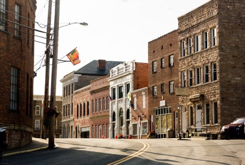 A quaint street lined with historic brick buildings and a colorful flag, bathed in warm sunlight.