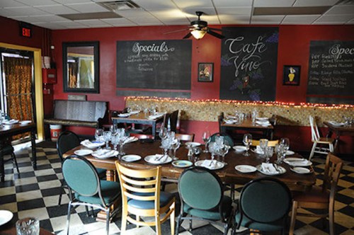 Cozy restaurant interior with checkered floor, tables set for dining, and chalkboard menus on the walls.