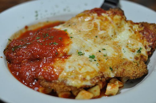 A plate of chicken parmesan topped with marinara sauce and melted cheese, garnished with parsley.