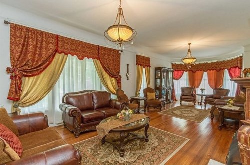 Elegant living room with rich curtains, leather sofas, a decorative table, and warm lighting. Cozy and inviting atmosphere.