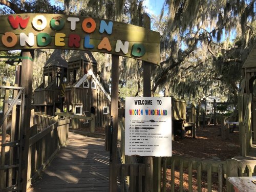 Colorful sign for "Wooton Wonderland" at a playground, surrounded by trees draped in Spanish moss.