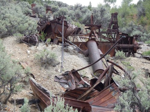 Rusty remnants of machinery scattered among sagebrush in a desolate landscape.