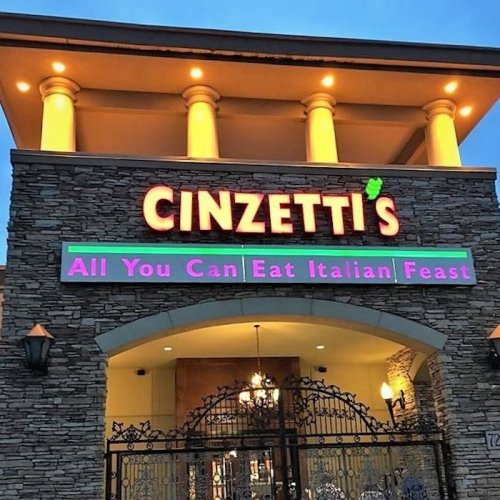 Sign for Cinzetti's restaurant featuring "All You Can Eat Italian Feast" in colorful lettering on a stone building.
