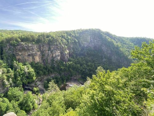 A scenic view of a lush green canyon with steep cliffs and a river winding through the valley below.