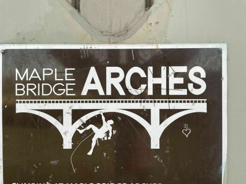 Sign for Maple Bridge featuring the word "ARCHES" and an illustration of a person climbing.