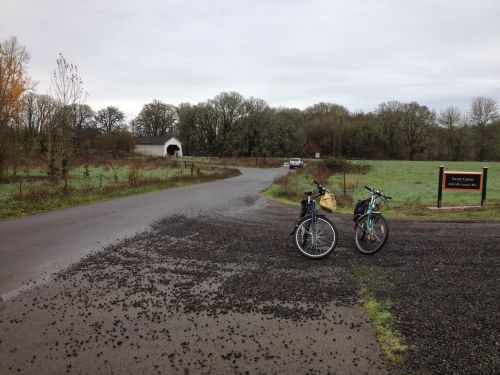 Two bicycles parked on a gravel road near a tunnel entrance, surrounded by trees and open fields.