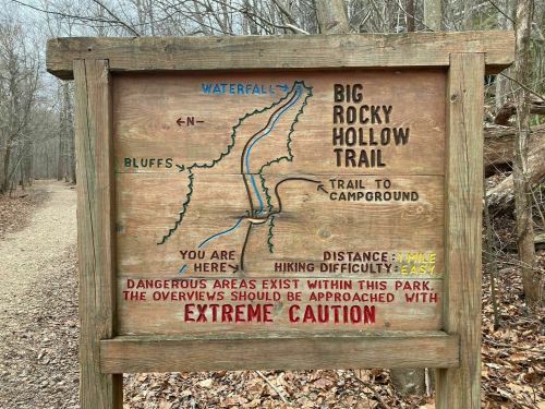 Wooden sign displaying a map of Big Rocky Hollow Trail, noting distance, difficulty, and caution for dangerous areas.