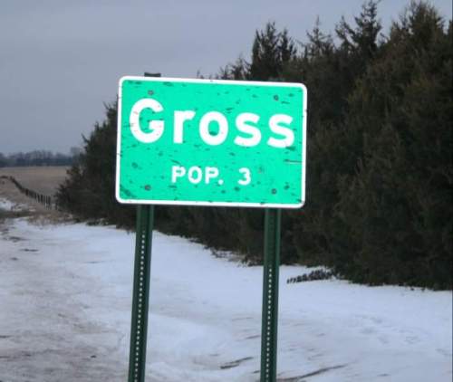 Sign for the town of Gross, population 3, with a snowy landscape in the background.