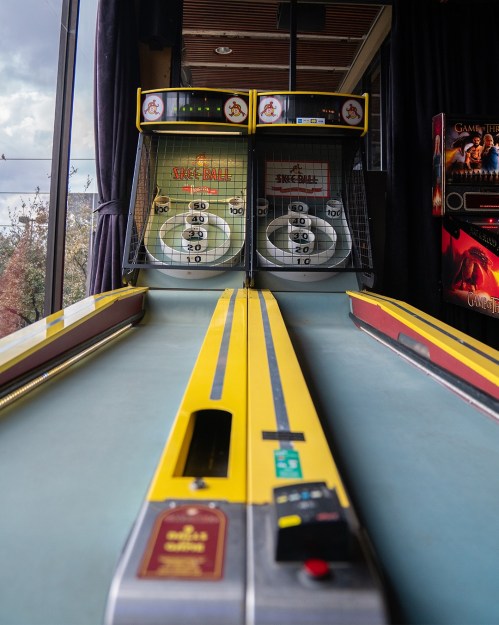 A view of a skee ball arcade game with two scoring targets and a smooth playing surface.