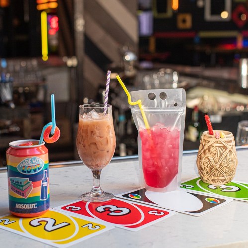 A variety of colorful drinks on a bar counter, with Uno cards in the foreground.