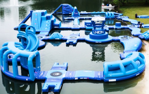 A large blue inflatable water park with various slides and obstacles set on a lake.