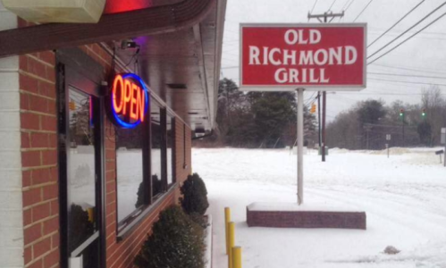 A snowy scene outside the Old Richmond Grill, featuring an "Open" neon sign and a clear view of the restaurant's sign.