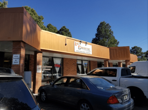 Exterior of a Mexican restaurant with a sign reading "Las Gorditas," featuring a clear blue sky and parked cars.