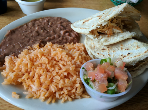 A plate of Mexican food featuring rice, refried beans, tortillas, and a side of pico de gallo.