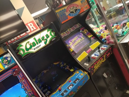 Two classic arcade machines: "Galaga" on the left and "Street Fighter II" on the right, in a colorful game room.